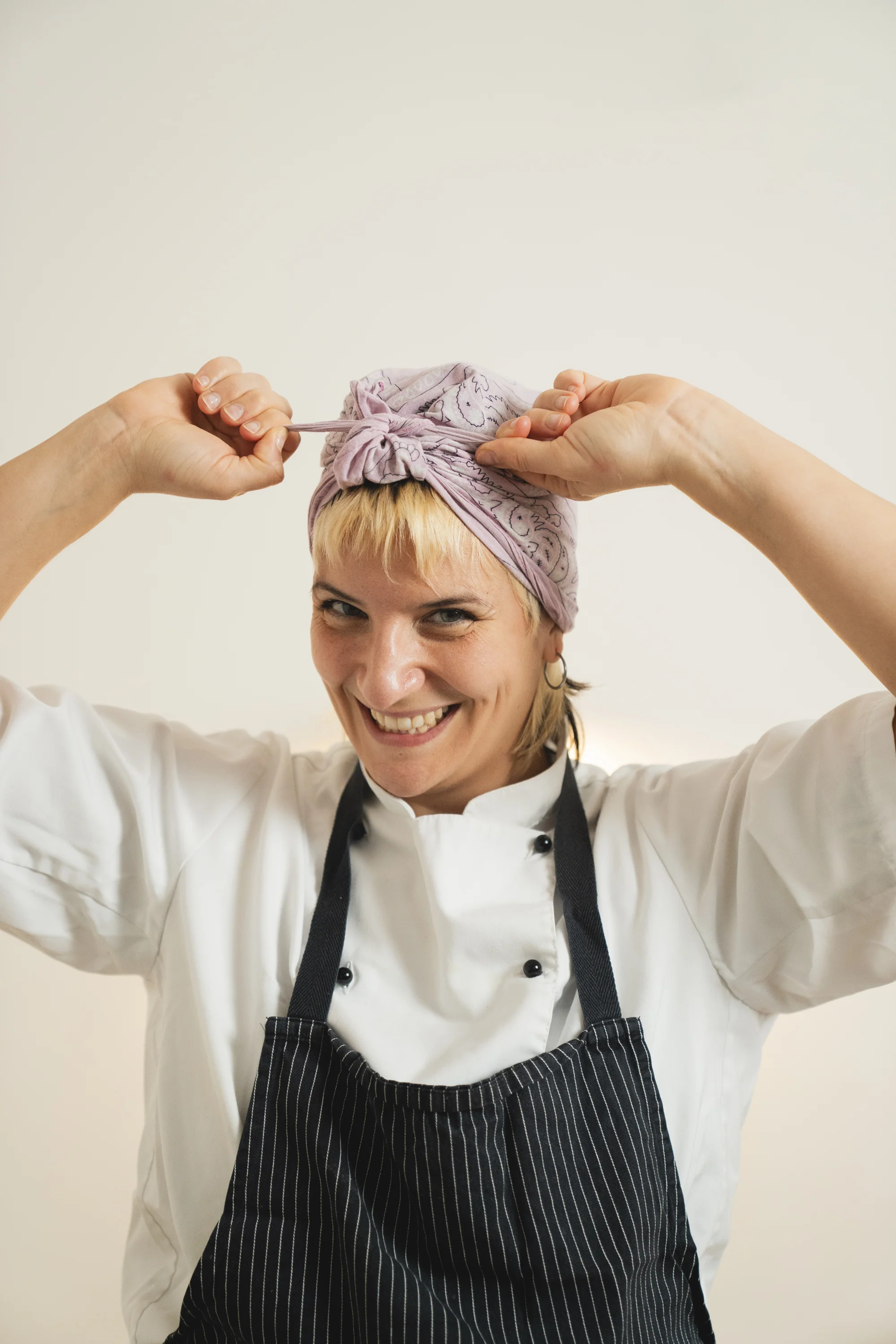 La chef Enza sorride mentre si annoda la bandana in testa